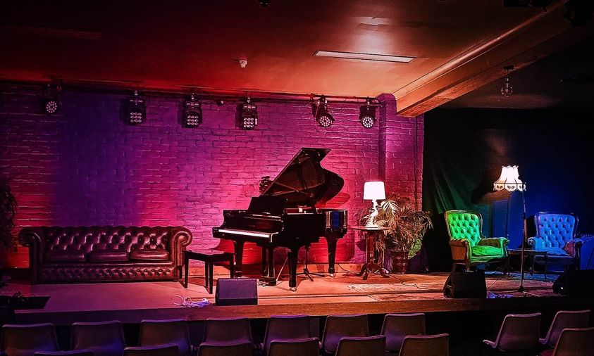 GRAND PIANO ON A STAGE WITH PURPLE LIGHTING